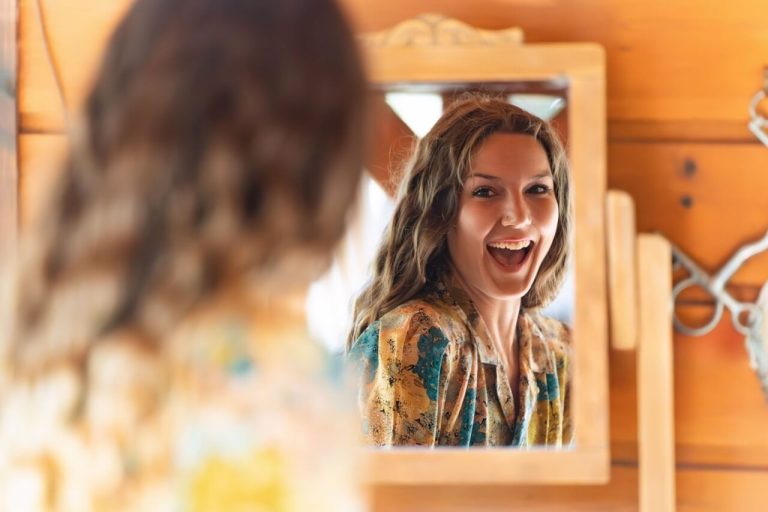 Unlock Self-Love: 20 Powerful Tips on How to Love Yourself woman smiling at reflection in mirror