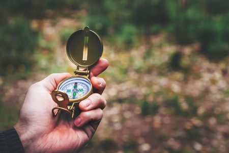 person looking at a compass in a forest